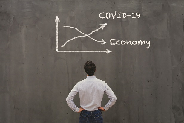 man looking at chalkboard with down arrow labeled economy and up arrow labeled COVID-19
