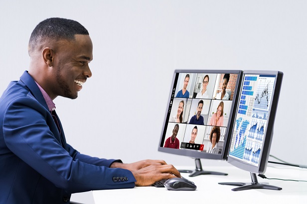 smiling man at computer having a virtual meeting while looking at financial charts