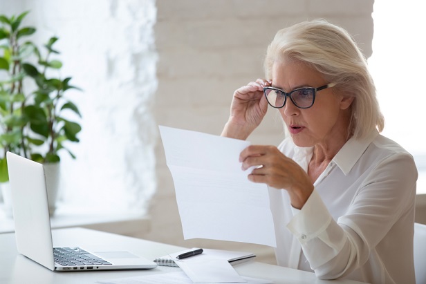 older woman looking at papers in shock