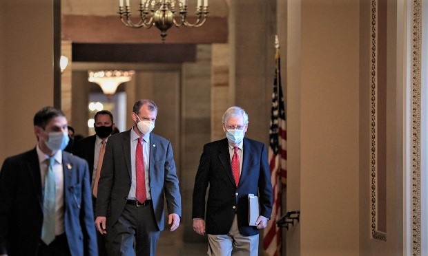Senate Majority Leader Mitch McConnell, a Republican from Kentucky, right, wears a protective mask while walking to the Senate floor at the U.S. Capitol in Washington Dec. 11, 2020. (Credit: Cheriss May/Bloomberg)