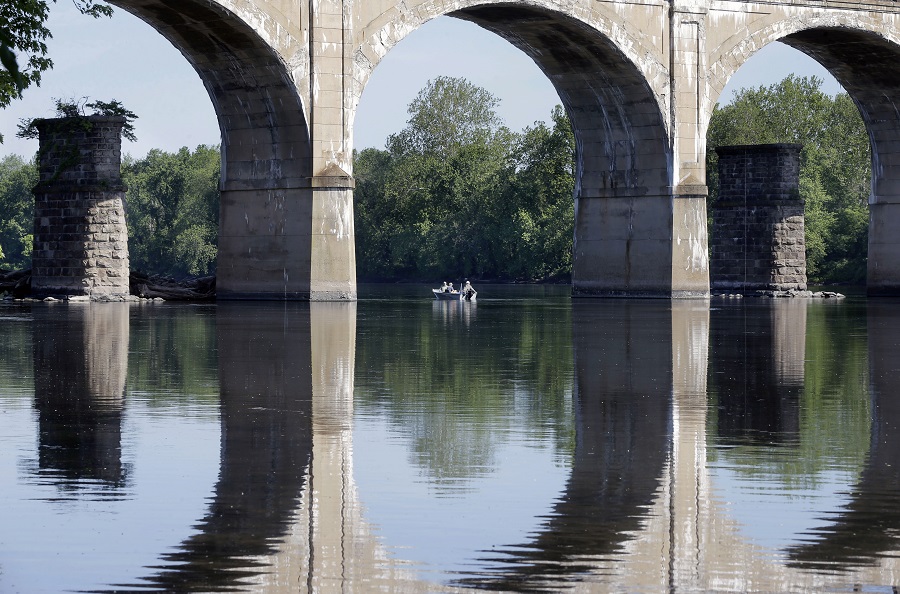 People fish from a boat near a bridge on the Delaware River, Sunday, May 24, 2015, in the West Trenton section of Ewing Township, N.J. (AP Photo/Mel Evans)