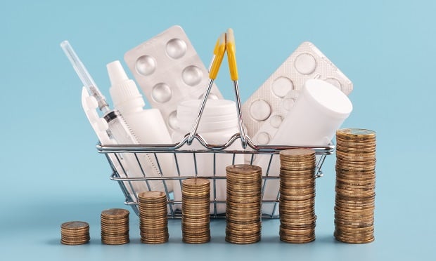 Basket of prescription drugs with stacks of coins in front