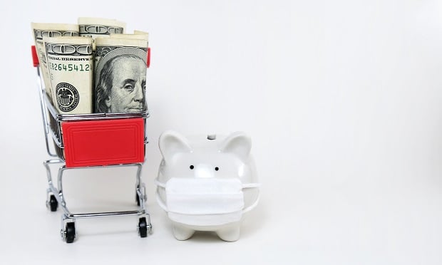 Piggy bank wearing mask next to shopping car with dollars