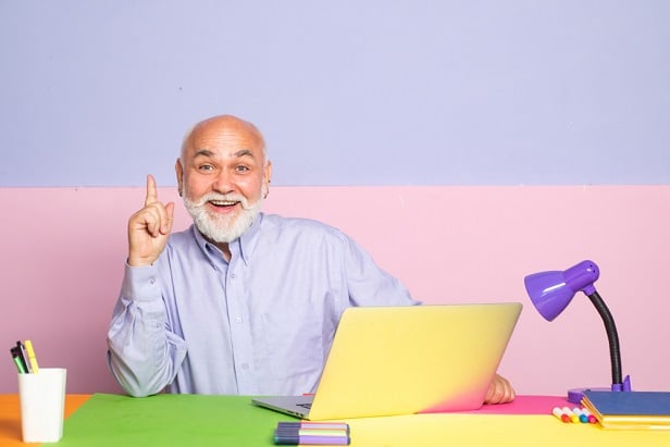 older bearded man in front of laptop looking happy