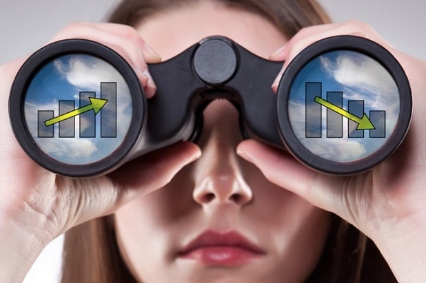 closeup of woman with binoculars against her face and charts are in the lenses