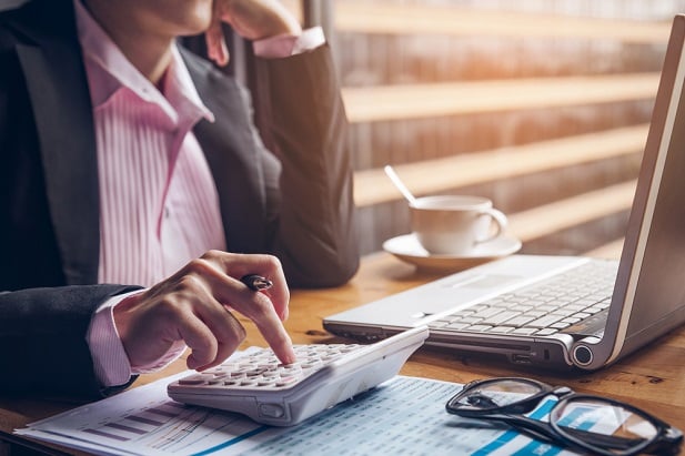torso of business woman at computer using calculator