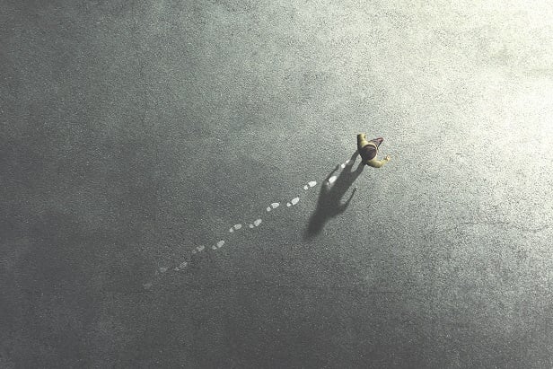 black and white drawing of person seen from above leaving footprints in the sand