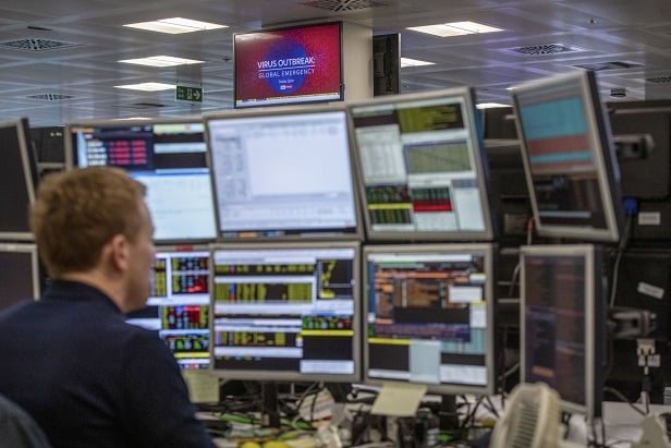 man at desk with multiple monitors alone in an office