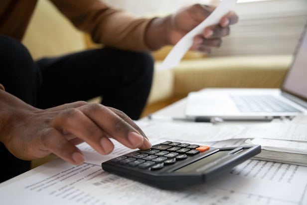 view of man's hands using a calculator and holding an investment or bank statement or bill