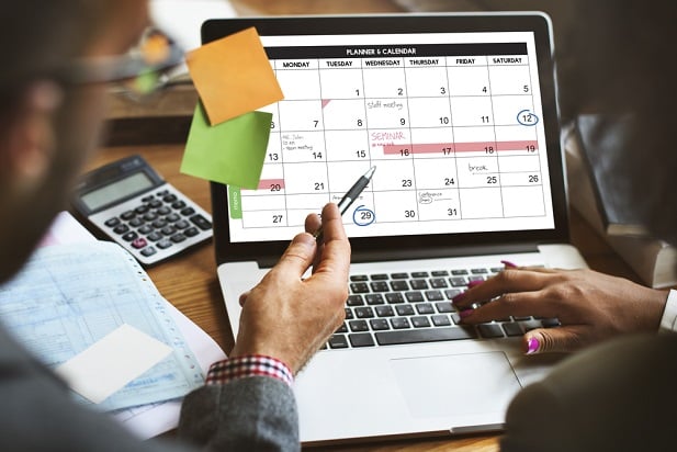 two people looking at calendar on laptop