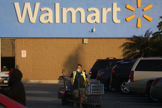 Walmart building seen from parking lot, with sign and worker