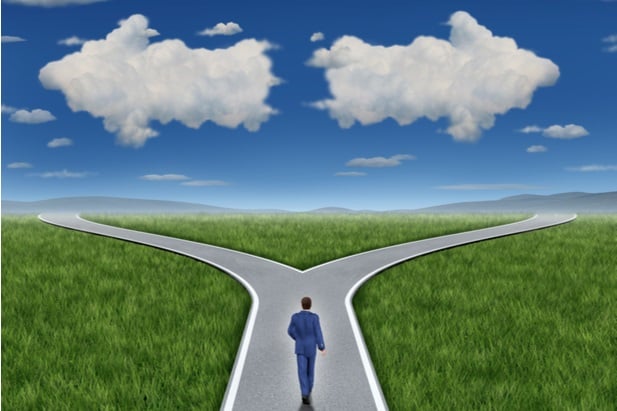 man on road that forks left and right with arrows made of clouds
