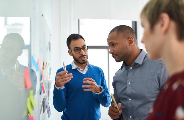 Diverse coworkers at board with markers planning