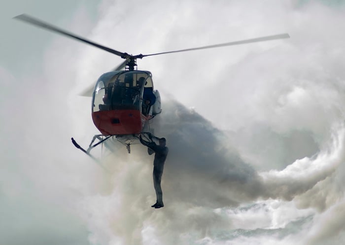 man hanging out of helicopter