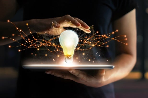 woman holding laptop with glowing lightbulb above it