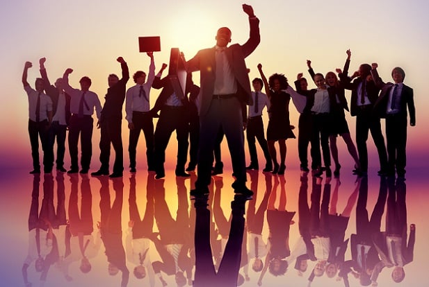 person leaping with briefcase in front of cheering people