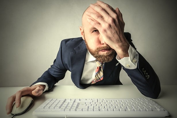 man at computer smacking forehead with his hand