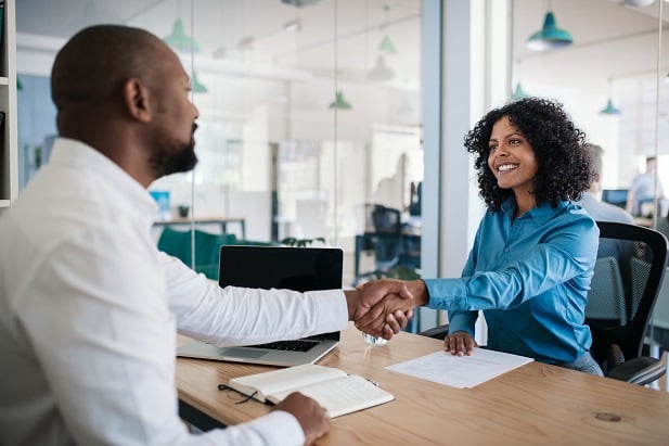woman and man across desk shaking hands