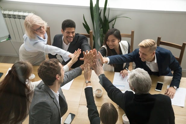 workers at table giving big high fives to each other