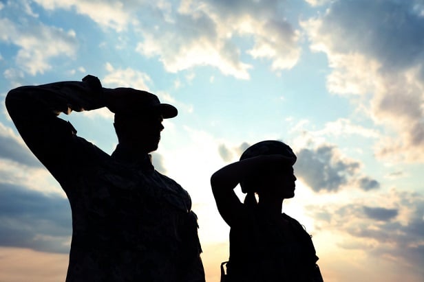 backlit man and woman saluting