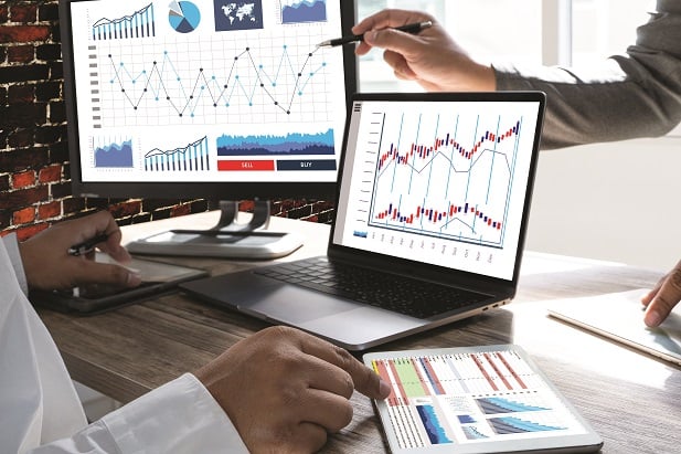 closeup of computer screen with charts and people's hands pointing