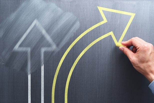 chalkboard with half-erased arrow and hand drawing new arrow