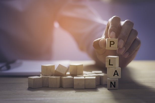 closeup of hand stacking blocks to spell Plan