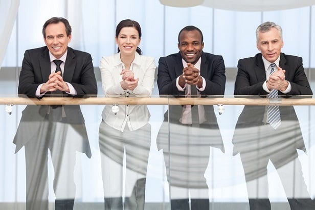 4 business professionals leaning on railing and smiling