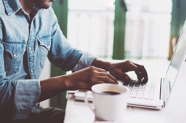 man with laptop and coffee cup working remotely