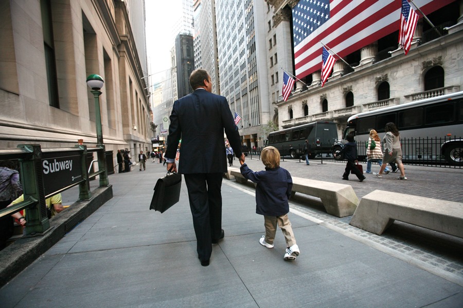 Business man and child walk along Wall Street