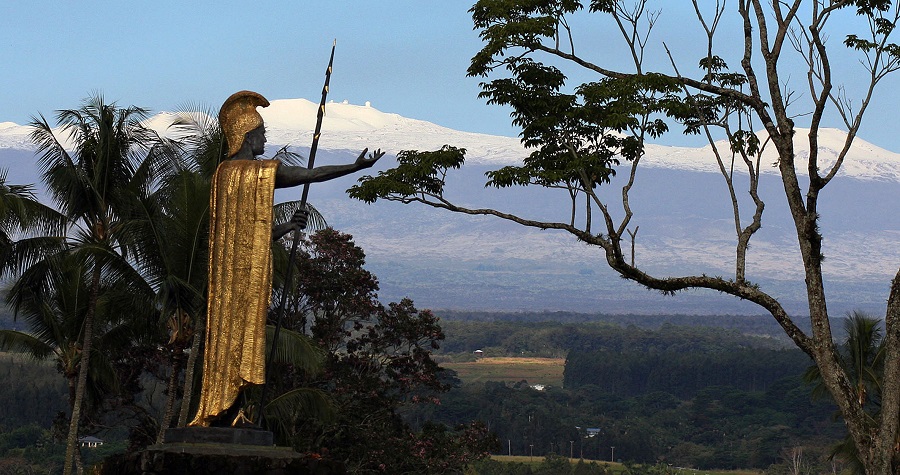 Snow on Mauna Kea is seen Friday Jan. 31, 2014, behind a statue of the Hawaiian King Kamehameha in Hilo, Hawaii. (AP Photo/Tim Wright)