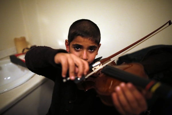  Jouan, last name not given, a Syrian Kurd 10-year-old refugee from Aleppo plays the violin. (AP Photo/Lefteris Pitarakis)