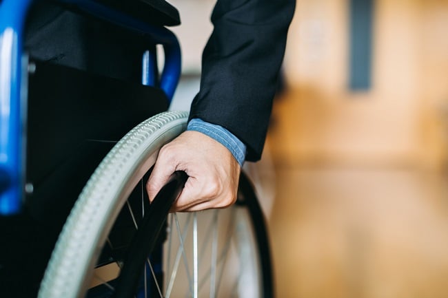 man with hand on wheelchair wheel