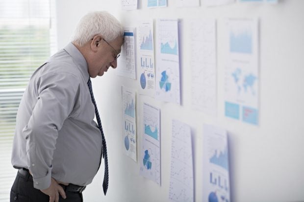 older man with forehead against wall