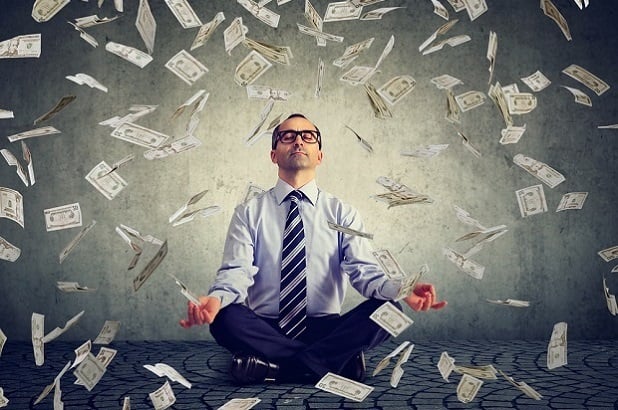 man meditating in shower of dollars