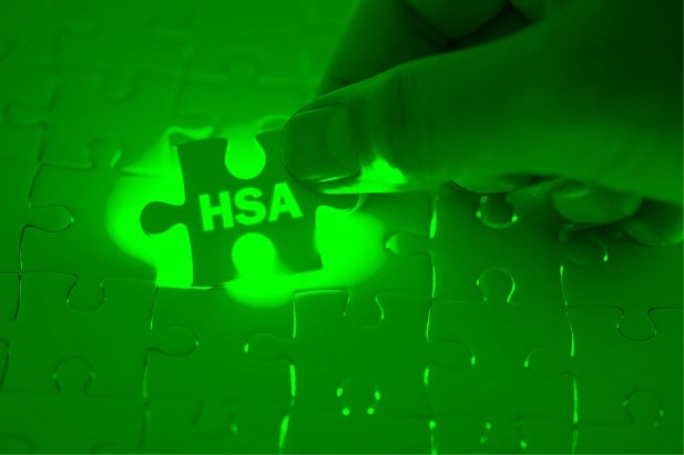 hand inserting HSA puzzle piece on green background