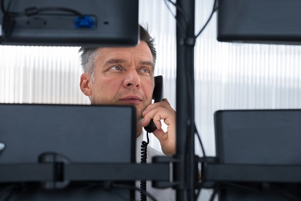 man on phone looking at 4 computer screens