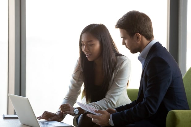 young female advisor at computer with young man