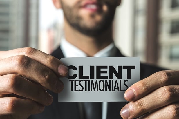 business man holding sign saying Client Testimonials