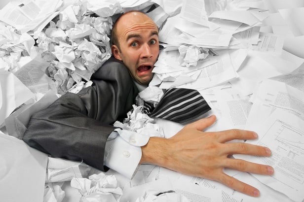 man drowning in papers