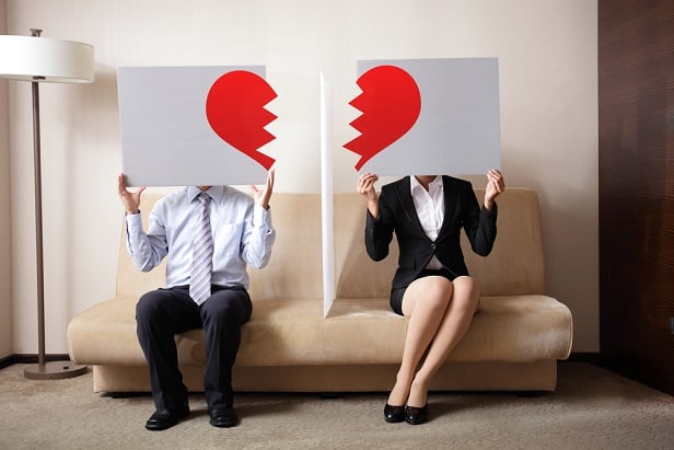 man and woman holding signs with half a heart symbol