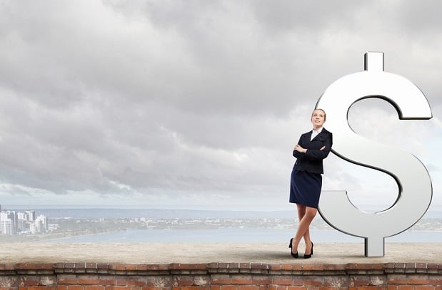 business woman leaning against giant dollar sign