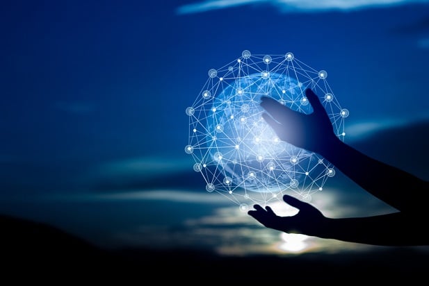 hands at twilight holding a globe of sparkling lights
