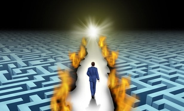Man walking down a path between mazes