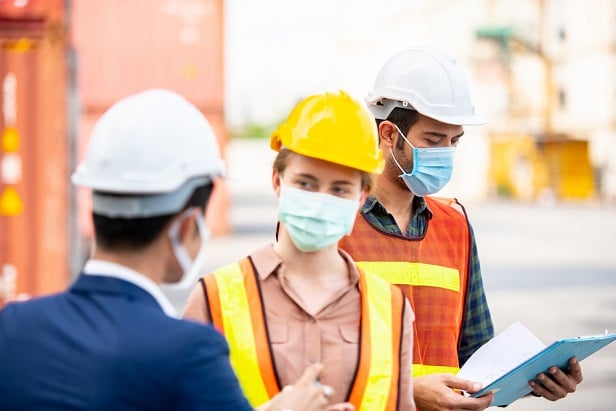 engineer and hard hat workers wearing face masks at job site
