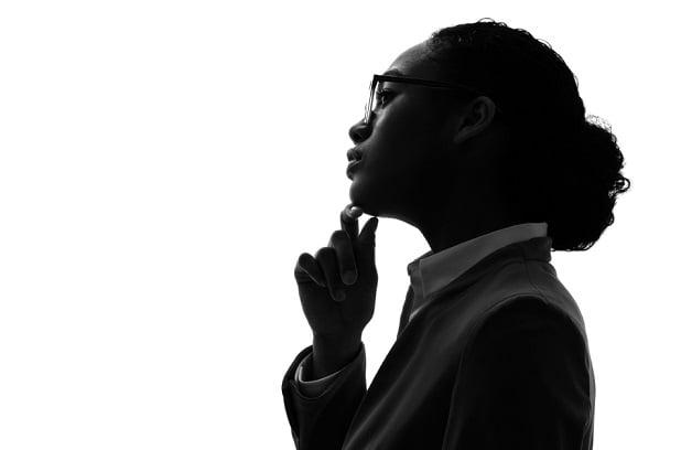 professional woman in profile with finger to chin, thinking