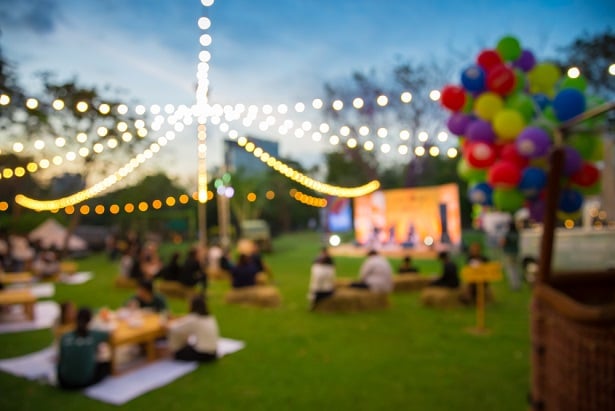 event outside on grass under lights with people space apart sitting on the grass