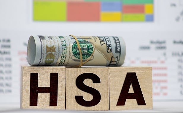 3 letter blocks spelling HSA on top of which rests a roll of rubberbanded currency