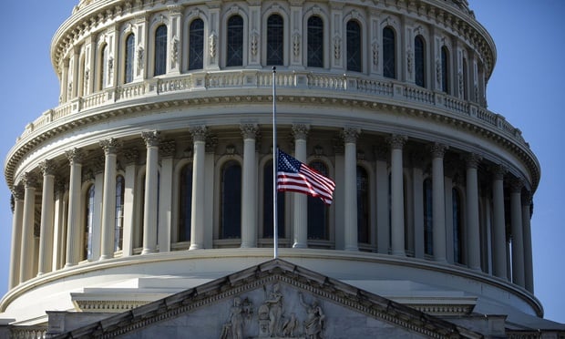 flag flying at half mast in front of closeup shot of the U.S. Capitol building