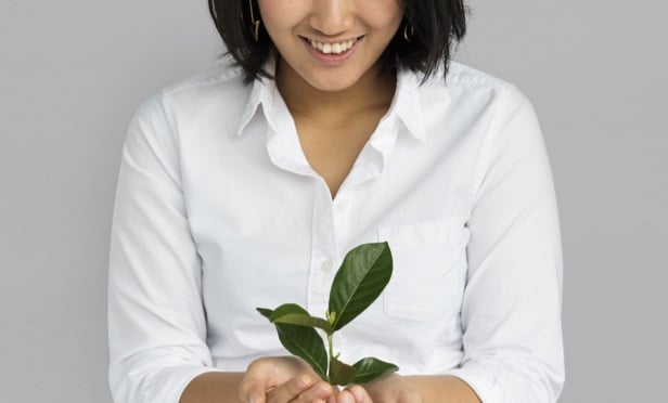 closeup of smiling woman holding seedling in hands
